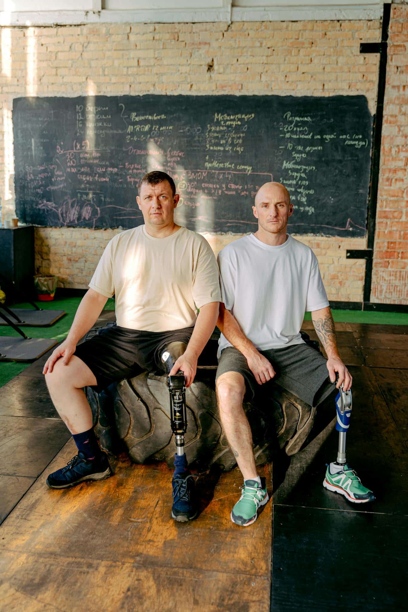 Two men with prosthetic legs sitting in a gym, symbolizing strength and resilience.